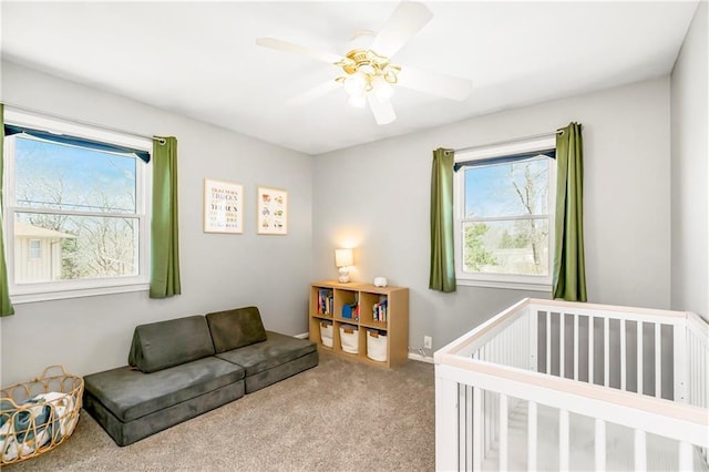 carpeted bedroom featuring a crib, multiple windows, and a ceiling fan