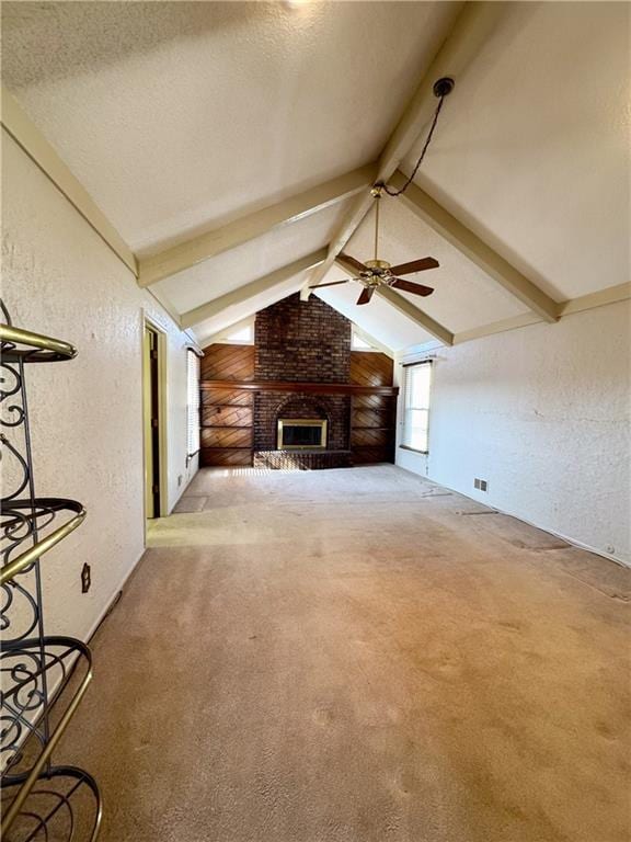 unfurnished living room featuring a ceiling fan, a textured ceiling, carpet, vaulted ceiling with beams, and a textured wall