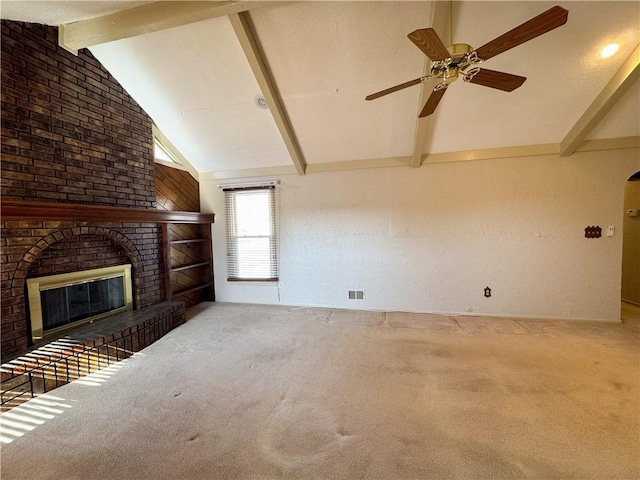 unfurnished living room with a ceiling fan, beamed ceiling, carpet, and a fireplace