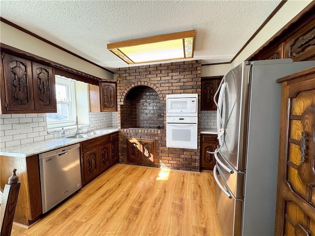 kitchen with backsplash, light wood-type flooring, light countertops, stainless steel appliances, and a sink