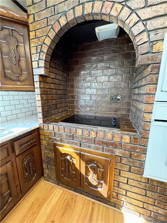 kitchen with light stone counters, tasteful backsplash, and light wood finished floors