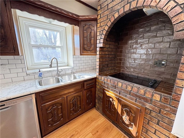 kitchen featuring a sink, backsplash, dishwasher, and light wood finished floors