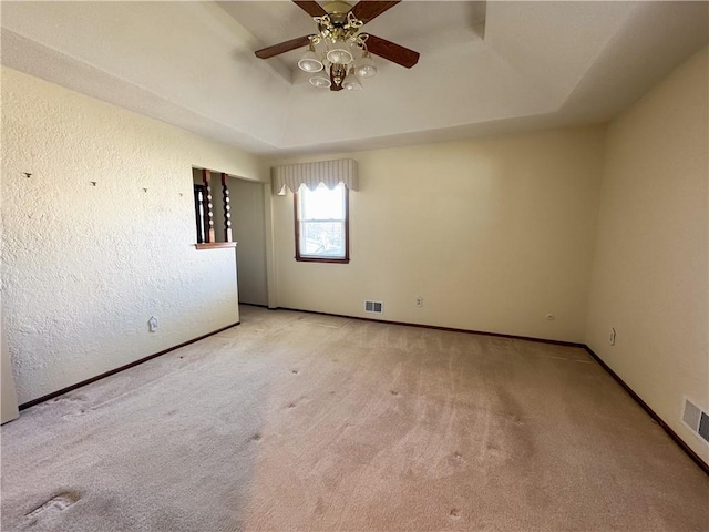 spare room featuring baseboards, a raised ceiling, carpet, and ceiling fan