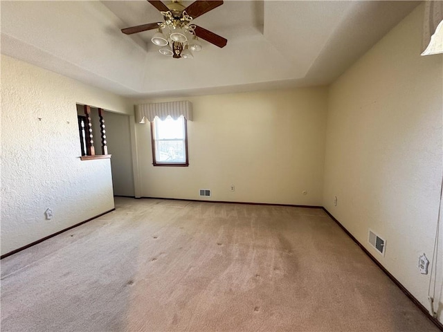 spare room featuring visible vents, ceiling fan, baseboards, carpet, and a tray ceiling