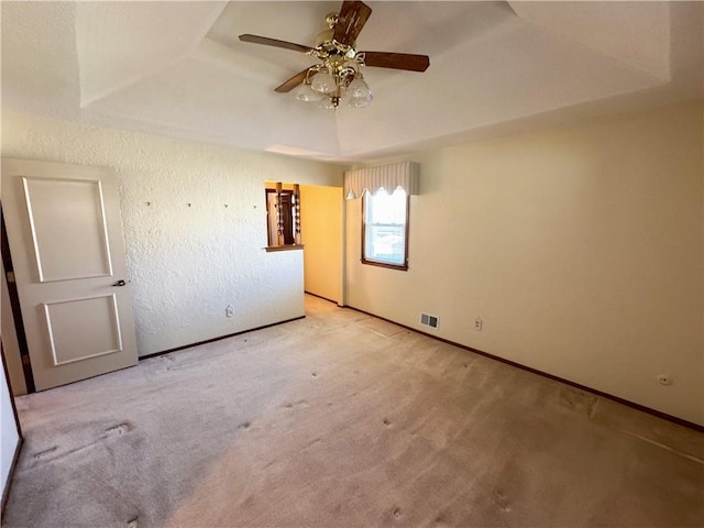 unfurnished bedroom with a raised ceiling, carpet floors, and a textured wall