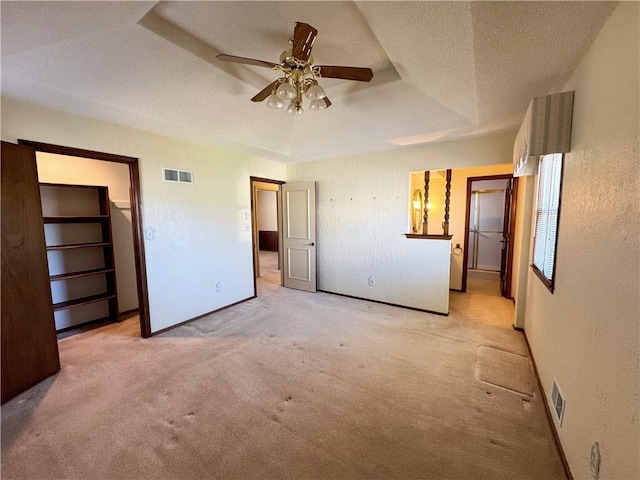 unfurnished bedroom featuring visible vents, a raised ceiling, a textured ceiling, and a textured wall