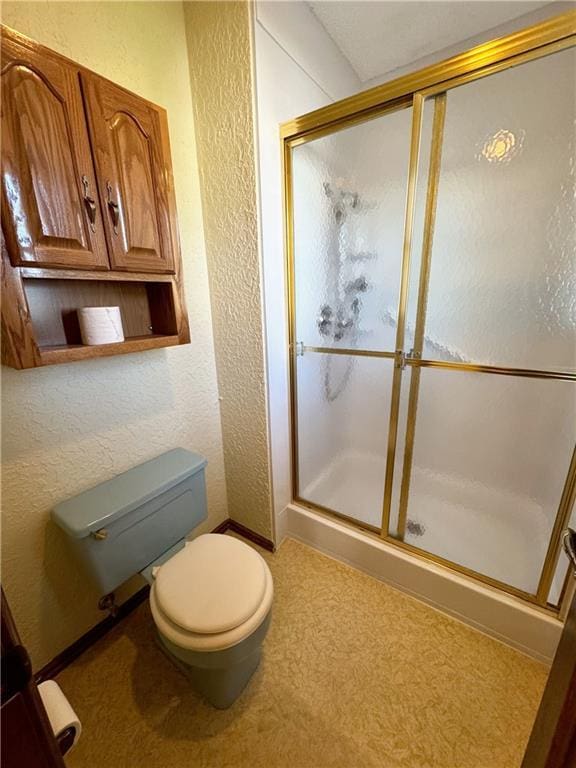 bathroom featuring toilet, a stall shower, and a textured wall