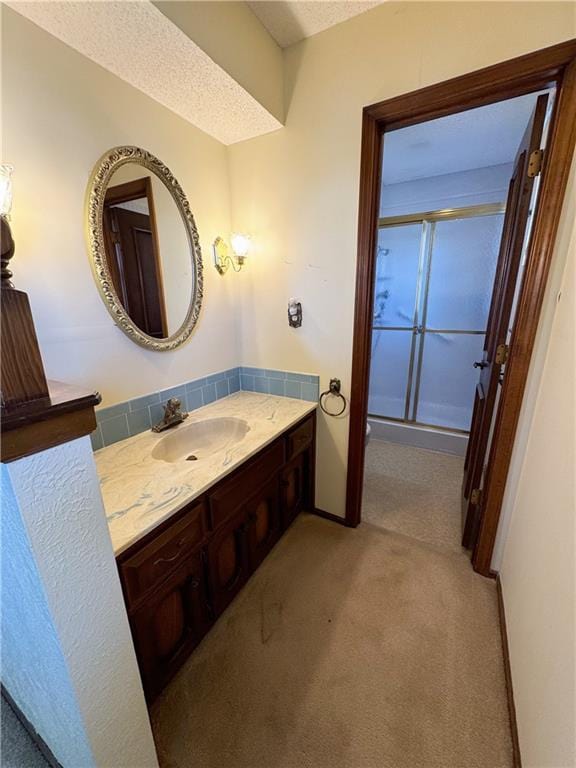 bathroom with vanity, an enclosed shower, and a textured ceiling