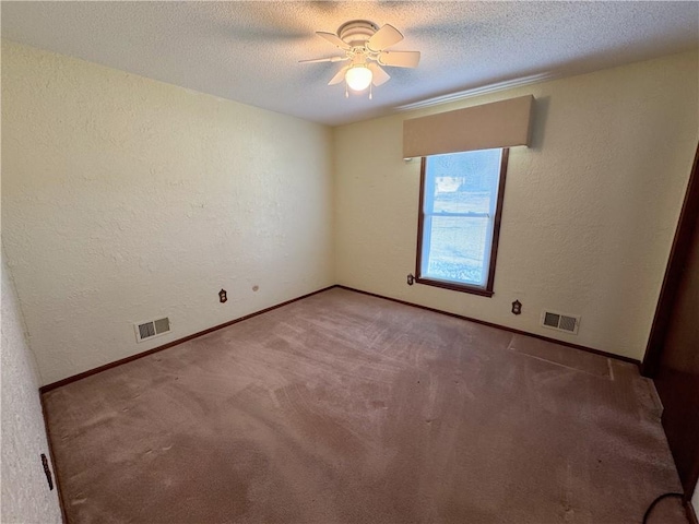 empty room featuring visible vents, a textured ceiling, and a textured wall