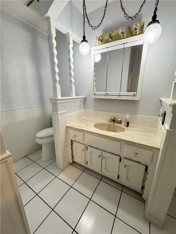 bathroom featuring a wainscoted wall, toilet, vanity, and tile patterned flooring