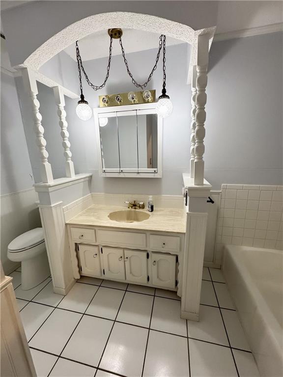 bathroom featuring tile patterned floors, toilet, a tub to relax in, and vanity