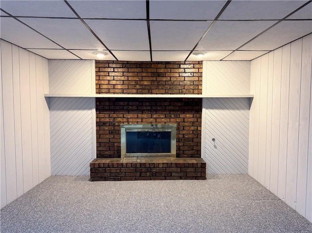 unfurnished living room with carpet floors, wooden walls, and a brick fireplace