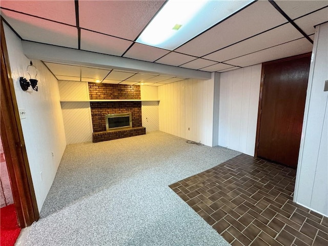 living room with wooden walls, a fireplace, a paneled ceiling, and dark colored carpet