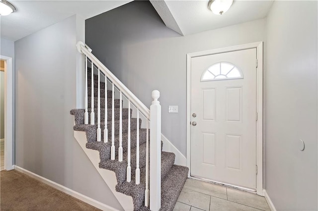 foyer featuring stairway, light tile patterned floors, and baseboards