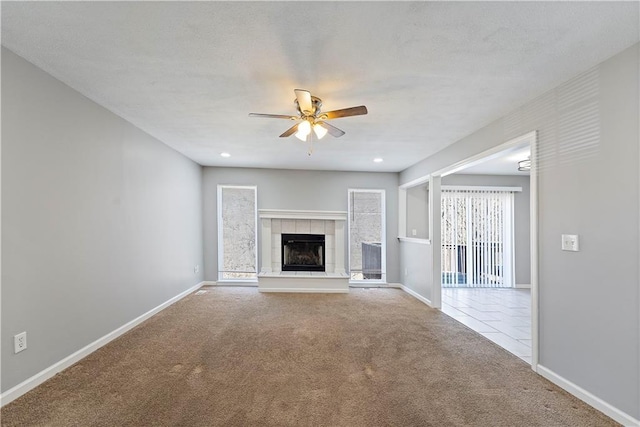 unfurnished living room with a fireplace, baseboards, carpet, and a ceiling fan