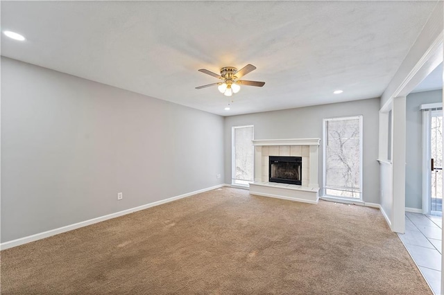 unfurnished living room featuring baseboards, light colored carpet, ceiling fan, and a fireplace