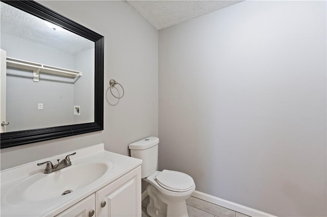 bathroom featuring toilet, a textured ceiling, tile patterned flooring, baseboards, and vanity