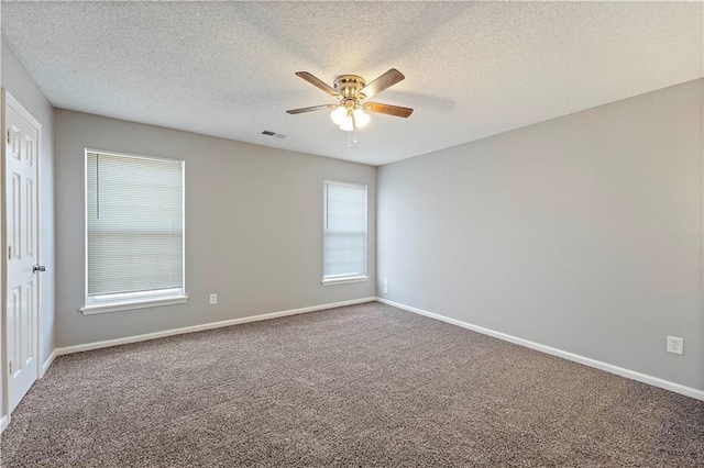 carpeted empty room featuring visible vents, a textured ceiling, baseboards, and ceiling fan