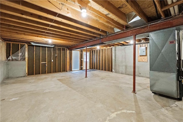 unfinished basement featuring electric panel and heating unit