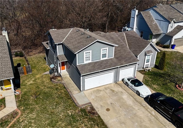 view of front of house with a front lawn, an attached garage, driveway, and a shingled roof