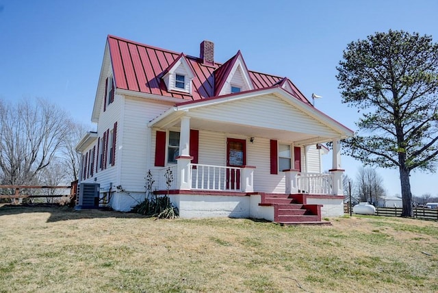 view of front facade featuring fence, a porch, a front yard, metal roof, and a standing seam roof