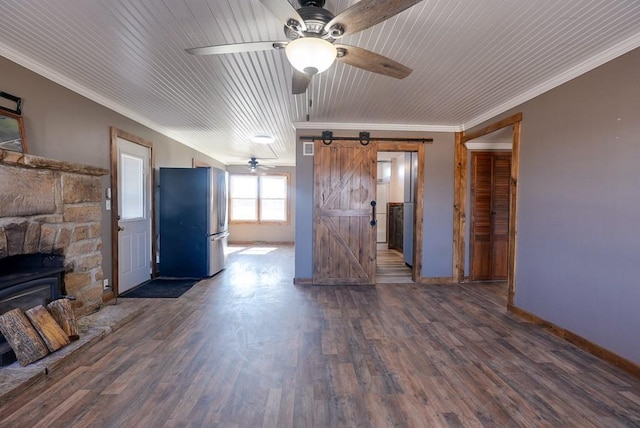 unfurnished living room featuring baseboards, a barn door, ornamental molding, wood finished floors, and a ceiling fan