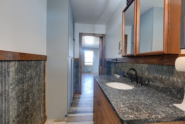 bathroom featuring vanity, wood finished floors, and tasteful backsplash