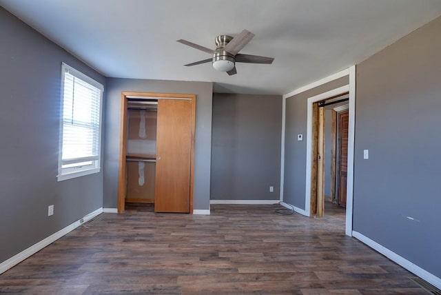 unfurnished bedroom featuring a closet, a ceiling fan, dark wood-type flooring, and baseboards