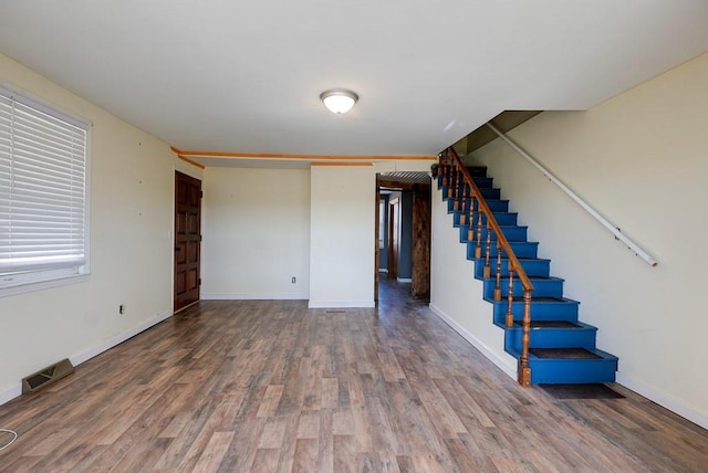 unfurnished living room with visible vents, baseboards, wood finished floors, and stairway