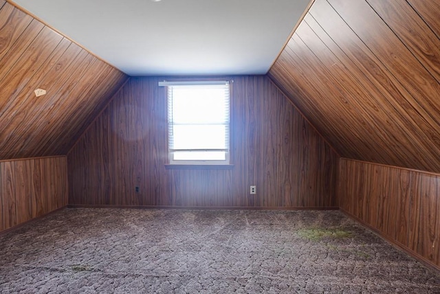 bonus room with vaulted ceiling, wood walls, and carpet floors