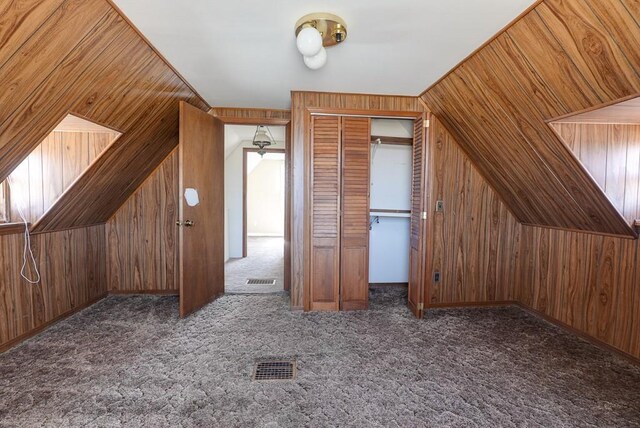 additional living space with wooden walls, carpet flooring, and visible vents