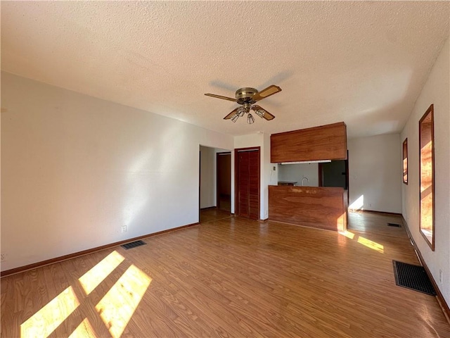 unfurnished living room featuring visible vents, baseboards, and wood finished floors