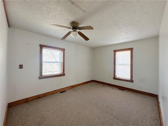 spare room featuring visible vents, carpet, a healthy amount of sunlight, and a textured ceiling