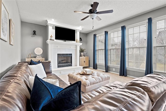 carpeted living room with baseboards, a fireplace, a textured ceiling, and ceiling fan