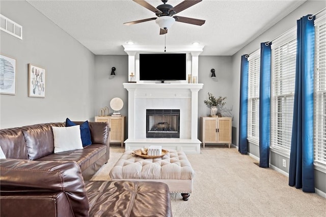 living room featuring visible vents, baseboards, carpet floors, a fireplace, and a textured ceiling