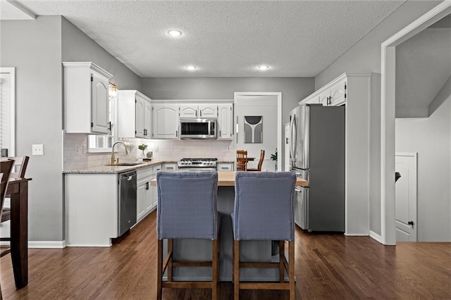 kitchen featuring dark wood finished floors, white cabinets, stainless steel appliances, and a sink