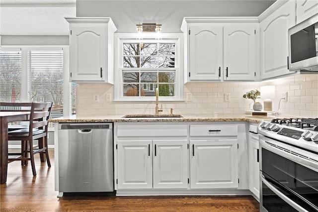 kitchen featuring a wealth of natural light, appliances with stainless steel finishes, white cabinetry, and a sink