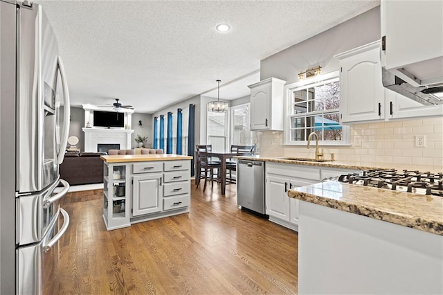 kitchen with a sink, stainless steel appliances, open floor plan, and light wood finished floors