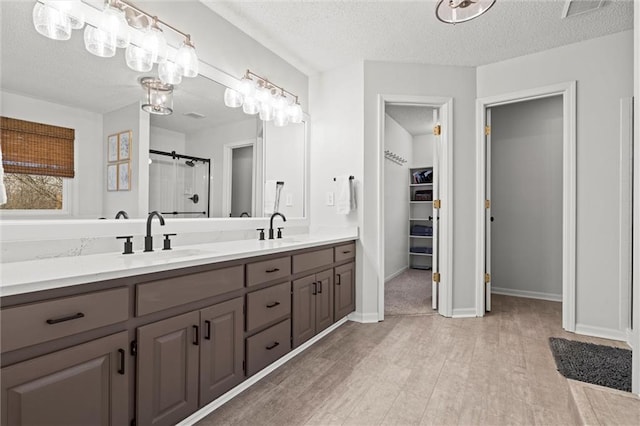 bathroom featuring a sink, a textured ceiling, walk in shower, and wood finished floors