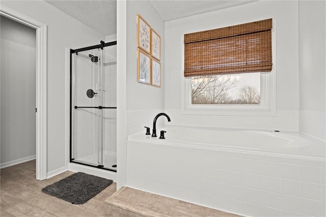 full bathroom featuring a shower stall, a textured ceiling, and a garden tub