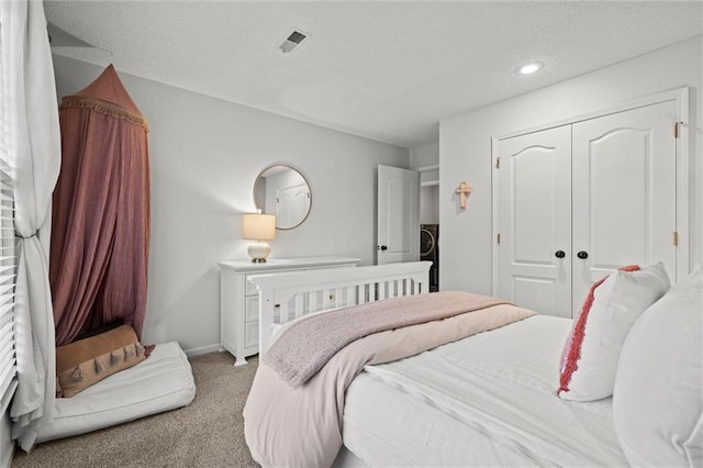 carpeted bedroom with visible vents, washer / clothes dryer, a textured ceiling, a closet, and baseboards