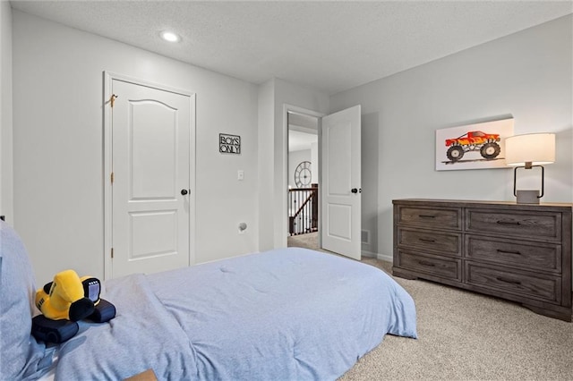 bedroom with recessed lighting, light colored carpet, a textured ceiling, and baseboards