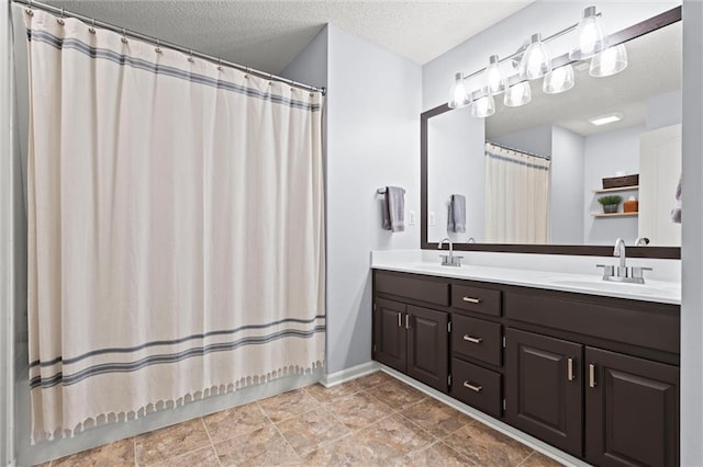 bathroom with a textured ceiling, double vanity, a shower with curtain, and a sink