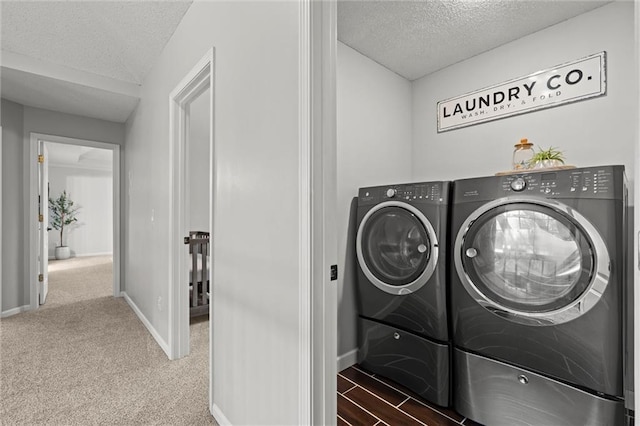 clothes washing area featuring baseboards, washer and clothes dryer, laundry area, carpet flooring, and a textured ceiling