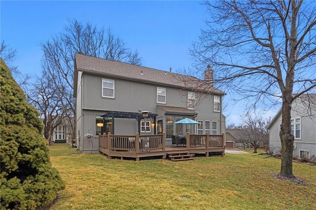 rear view of property with a shingled roof, a wooden deck, a lawn, and a chimney