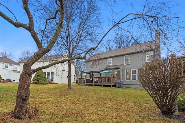 rear view of house with a chimney, a wooden deck, and a yard