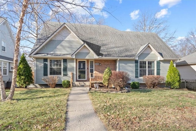 view of front facade featuring brick siding, a front yard, and roof with shingles