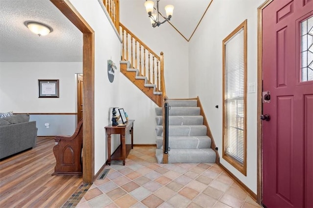 foyer entrance with baseboards, visible vents, an inviting chandelier, stairs, and a textured ceiling