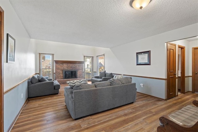 living area with baseboards, a textured ceiling, wood finished floors, and a fireplace