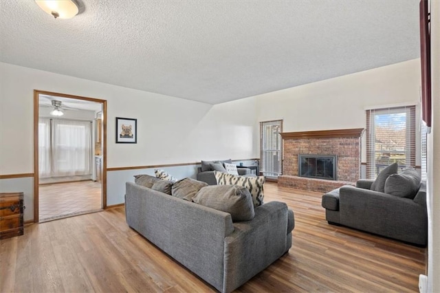 living room featuring a fireplace, a textured ceiling, and wood finished floors